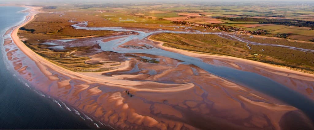 Aerial view of Brancaster Staithe harbour, creeks and salt marshes at sunset