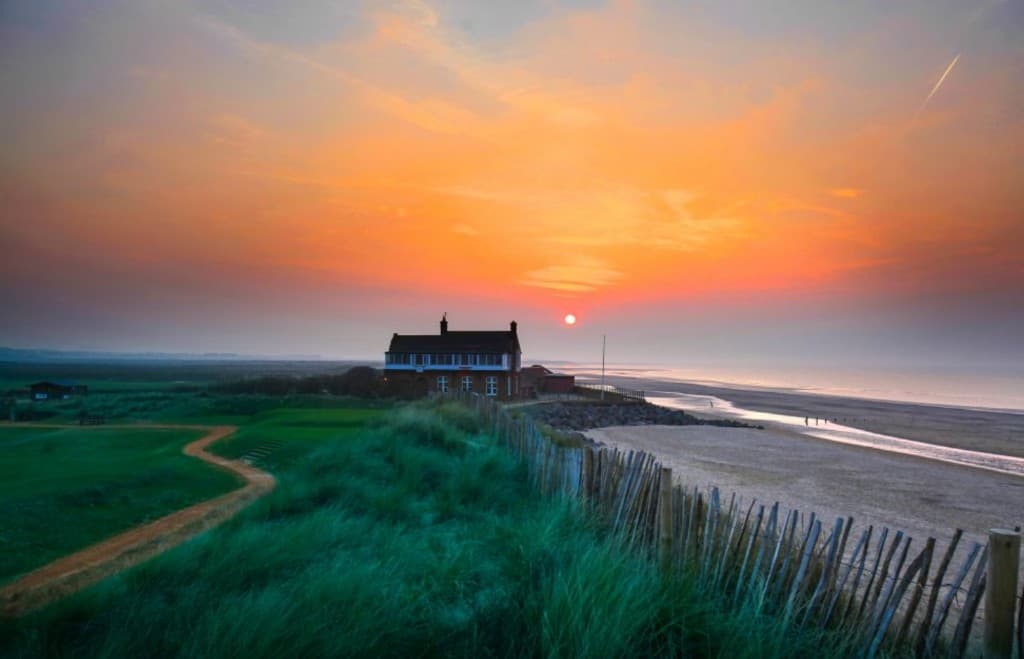 Royal West Norfolk Golf Club clubhouse at sunset beside Brancaster beach